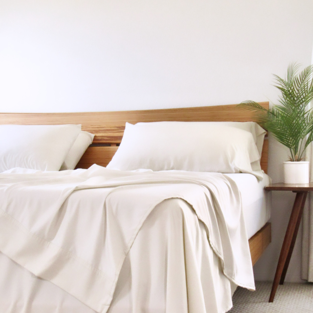 Cream Copper Infused Bamboo Pillowcase Set on a wooden bed with plant accent.